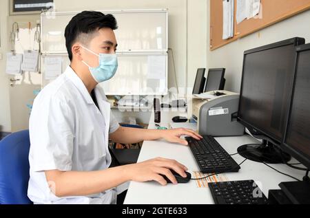 Pékin, Chine. 1er octobre 2021. (211002) -- BEIJING, 2 octobre 2021 (Xinhua) -- Ma Yuan vérifie les informations d'un patient sur un ordinateur à l'hôpital Haidian de Beijing, capitale de la Chine, le 1er octobre 2021. Ma Yuan, 28 ans, est chirurgien orthopédique à l'hôpital Haidian de Beijing. Le premier jour de la fête nationale, Ma était occupé comme d'habitude, en ajustant les prescriptions médicales, en admettant et en traitant les patients d'urgence et en rédigeant les dossiers médicaux. En tant que travailleur médical de première ligne, Ma a été utilisé à la vie comme ceci. Bien qu'il ait moins de temps pour accompagner sa famille pendant les vacances, Ma estime que ses efforts Banque D'Images