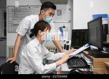 Pékin, Chine. 1er octobre 2021. (211002) -- BEIJING, 2 octobre 2021 (Xinhua) -- Ma Yuan (retour) vérifie les informations d'un patient sur un ordinateur à l'hôpital Haidian de Beijing, capitale de la Chine, le 1er octobre 2021. Ma Yuan, 28 ans, est chirurgien orthopédique à l'hôpital Haidian de Beijing. Le premier jour de la fête nationale, Ma était occupé comme d'habitude, en ajustant les prescriptions médicales, en admettant et en traitant les patients d'urgence et en rédigeant les dossiers médicaux. En tant que travailleur médical de première ligne, Ma a été utilisé à la vie comme ceci. Bien qu'il ait moins de temps pour accompagner sa famille pendant les vacances, Ma estime que son Banque D'Images
