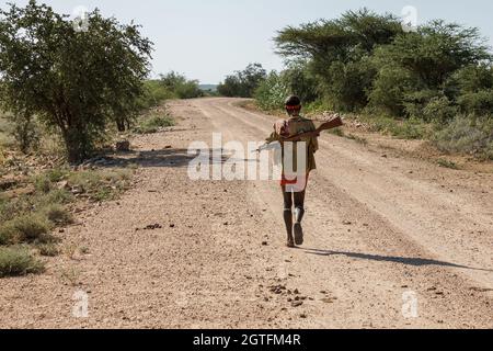 Omo Valley, Ethiopie - 10 décembre 2013 : un homme non identifié de la tribu Hamer avec un fusil marche le long de la route. Banque D'Images