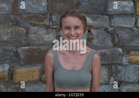 Portrait d'une jeune femme blonde caucasienne heureuse en crop top sur fond de pierre. Concept des émotions humaines. Amusé, joyeux, jeune fille, souriant, heureux Banque D'Images