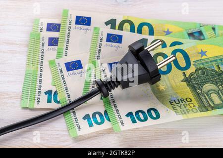Fiche électrique noire sur cent billets en euros. Augmentation du coût de l'électricité pour les clients résidentiels et les utilisateurs professionnels. Paiement de l'électricité Banque D'Images