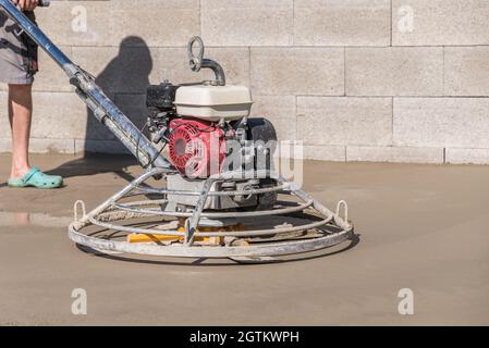 Bricklayer à l'aide D'Un moulin à béton pour lisser le béton Banque D'Images