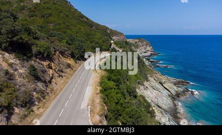 Vue aérienne des ruines de la tour Génoise ronde de l'Osse sur le Cap Corse, Corse, France - vestiges d'un belvédère médiéval dans la courbe d'une route Banque D'Images