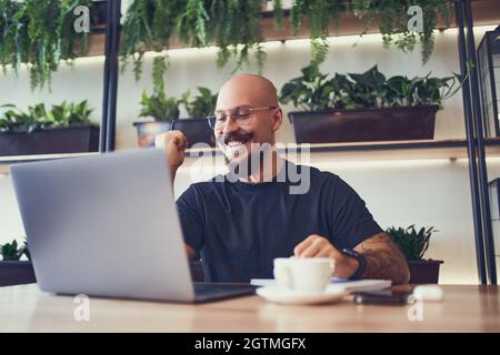 Homme d'affaires ou étudiant utilise l'ordinateur portable dans le café montre oui geste tout en regarde l'écran de l'ordinateur portable Banque D'Images