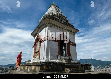 Kirtipur, Népal - octobre 2021 : une femme à côté d'un petit temple hindou à Kirtipur le 2 octobre 2021 dans la vallée de Katmandou, au Népal. Banque D'Images