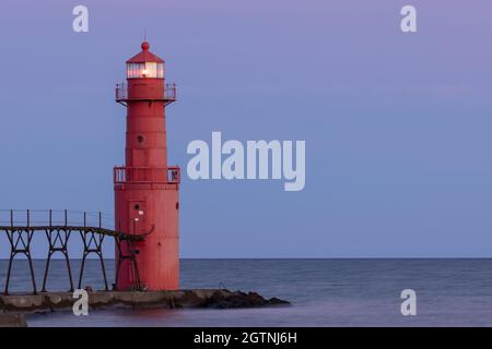 Un phare rouge de Breakwater illuminé la nuit le long du lac Michigan Banque D'Images