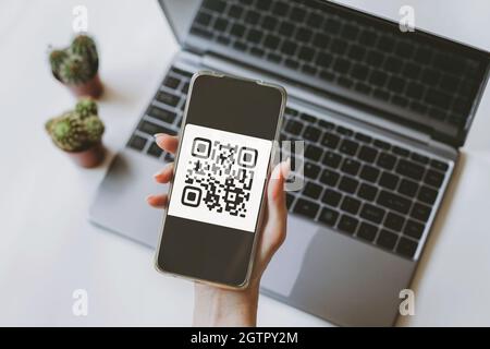 Concept de technologie de lecture de code QR avec paiement et sans espèces. La main féminine utilise un téléphone portable pour scanner un code QR. Banque D'Images