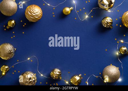Cadre de Noël avec décorations dorées, boules, guirlande, confettis sur fond bleu. Célébration de Noël, hiver, concept du nouvel an. Chris Banque D'Images