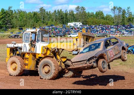 Norton, N.-B., Canada - 11 septembre 2021 : courses de piste de terre au circuit Redneck. Des machines lourdes transportent une voiture brisée hors de la voie. Banque D'Images