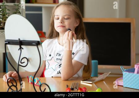 Belle fille avec le syndrome de Down peignant ses cheveux devant un miroir à la maison Banque D'Images