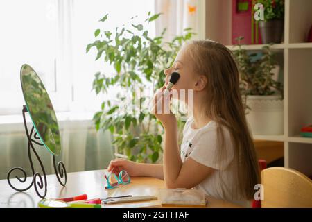 Belle fille avec le syndrome de Down peignant ses cheveux devant un miroir à la maison Banque D'Images