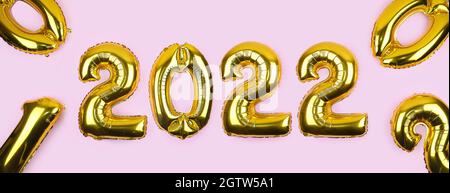 2022 banderoles avec ballons dorés sur fond rose. Numéros 2022 ballons d'or sur le mur rose . Carte du nouvel an. Bonne fête du nouvel an Banque D'Images