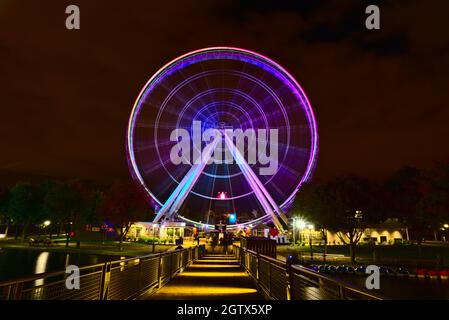 Effet de flou de la grande roue de Montréal dans le Vieux-Port à l'heure bleue au crépuscule. L'arrière-plan est ciel nuageux et nuageux. Le premier plan est le col d'automne Banque D'Images