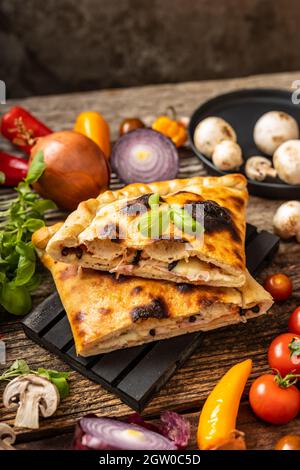 Pizza en tranches calzone servie sur une palette noire Banque D'Images