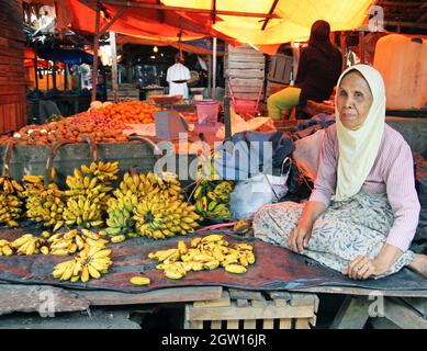 Une vieille femme qui vend des bananes dans un marché en décrochage à Padang, dans l'ouest de Sumatra, en Indonésie.Elle est assise à pattes croisées et porte un hijab musulman, Banque D'Images