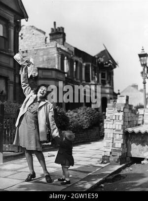 Une femme avec un jeune enfant qui applaudisse dans la rue le jour de la victoire en Europe, le 8 mai 1945 Banque D'Images