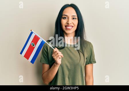 Jeune fille hispanique portant le drapeau du costa rica a l'air positif et heureux debout et souriant avec un sourire confiant montrant des dents Banque D'Images