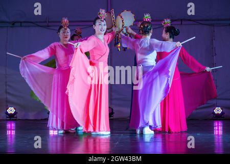 Un groupe de femmes coréennes dans des robes hanbok traditionnelles, dansant sur scène avec sogo (tambours à main) Banque D'Images
