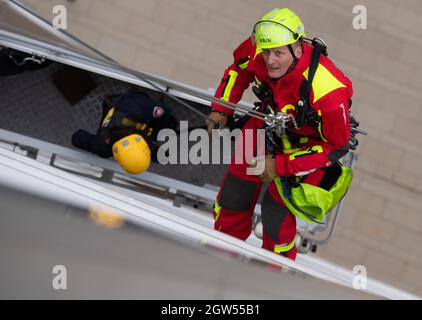 29 septembre 2021, Hessen, Francfort-sur-le-main : un pompier de l'équipe de sauvetage en hauteur de la brigade des pompiers de Francfort descend du toit de la tour Winx vers une gondole de nettoyage de fenêtres pendant un exercice. La moindre erreur peut signifier la catastrophe pour les hommes de l'équipe de sauvetage en hauteur lors de leurs missions sur les gratte-ciels de la métropole bancaire. (À dpa « High up - height resevers in action in Extreme situations ») photo : Boris Roessler/dpa Banque D'Images