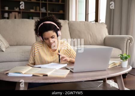 Femme ethnique africaine millénaire ciblée dans le casque étudiant à la maison. Banque D'Images