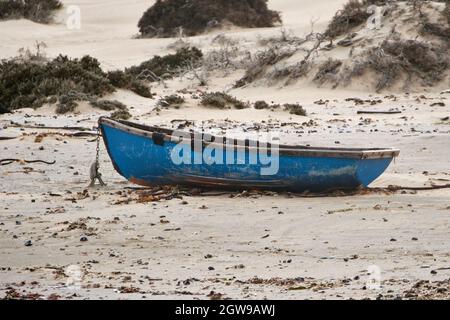 Simple bateau de pêche en bois attaché avec une chaîne sur la plage. Banque D'Images