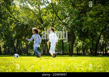 image cinématographique d'une famille des émirats passant du temps dans le parc. Frère et sœur jouant au football dans l'herbe Banque D'Images