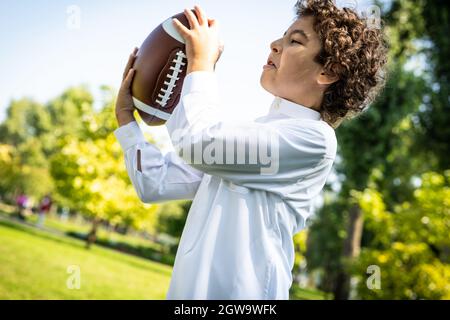 image cinématographique d'une famille des émirats passant du temps dans le parc. Frère et sœur jouant au football dans l'herbe Banque D'Images