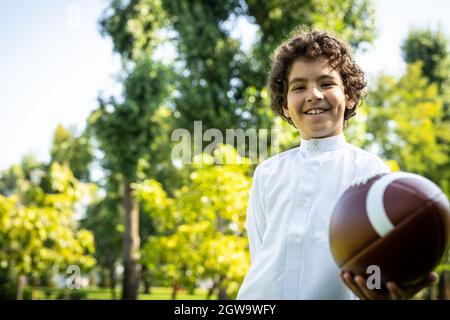 image cinématographique d'une famille des émirats passant du temps dans le parc. Frère et sœur jouant au football dans l'herbe Banque D'Images