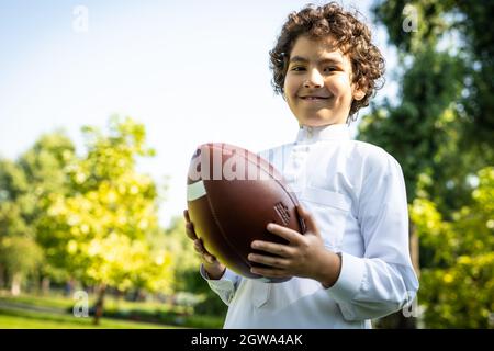 image cinématographique d'une famille des émirats passant du temps dans le parc. Frère et sœur jouant au football dans l'herbe Banque D'Images