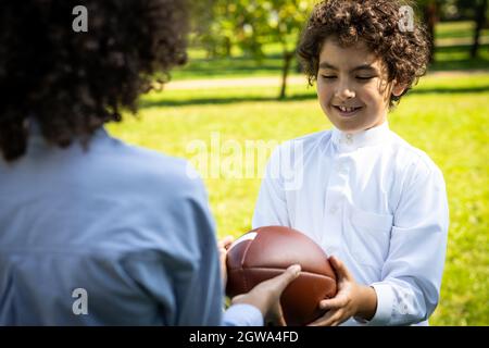 image cinématographique d'une famille des émirats passant du temps dans le parc. Frère et sœur jouant au football dans l'herbe Banque D'Images