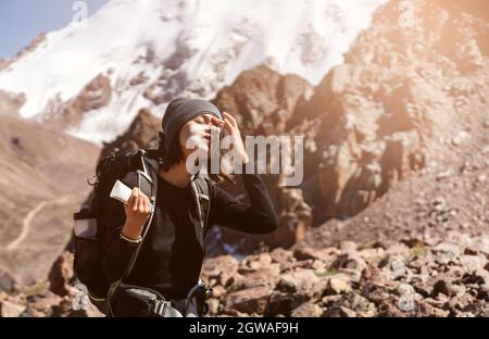 Fille applique de la crème solaire sur ses mains et le visage dans les montagnes. Banque D'Images