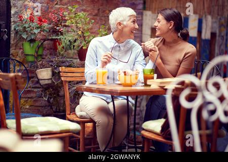 concept de relation mère-fille : deux femmes caucasiennes, âgées et jeunes, parlant, se regardant, souriant. Banque D'Images