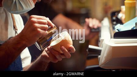 compétences du barista. verser du lait chaud dans une tasse de cappuccino. employé professionnel du bar à café Banque D'Images