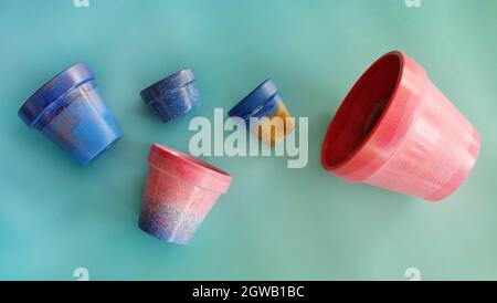 Plat de cinq pots en terre cuite colorés de différentes tailles.Peint en bleu, rose et or. Banque D'Images