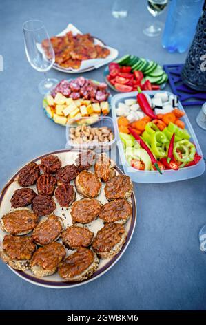 Assortiment de canapés, tapas, légumes, noix, fromage, salami et tartiner sur le pain, boisson sur la table de fête bleue. Banque D'Images