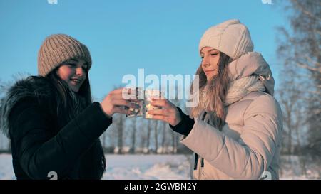 Deux amis boivent du thé chaud en hiver et des verres à clin d'œil. Banque D'Images