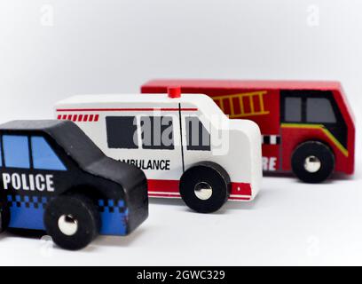 Les véhicules d'urgence en bois sont mis sur un fond blanc.Les jouets sont faits simplement.La police, l'ambulance et le moteur d'incendie sont alignés Banque D'Images