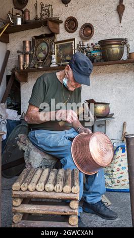 Un ouvrier du métal âgé travaille à la fabrication de casseroles et de poêles en cuivre dans son atelier dans la ville de Randazzo, Sicile, Italie Banque D'Images