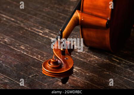 Partie supérieure en spirale d'un violoncelle reposant sur la scène en diagonale. Éclairage tamisé. Espace négatif sur la gauche Banque D'Images