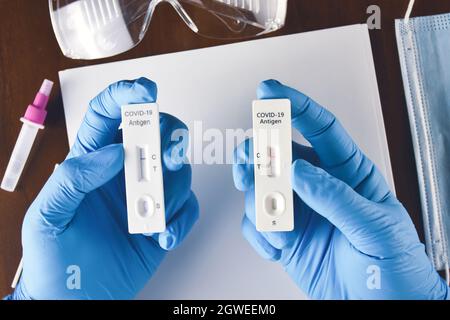 Un travailleur médical compare les résultats de test positifs et négatifs Covid-19 du kit de test rapide de l'antigène sur le bureau et sur les accessoires de laboratoire Banque D'Images