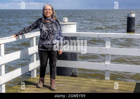 Medemblik, Noord-Hollande, pays-Bas. 14 avril 2021. Femelle touriste se tenant sur la jetée, l'horizon sur l'Ijsselmeer en arrière-plan, décontracté s Banque D'Images