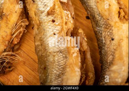 Petit poisson frit sur un panneau en bois, gros plan, sélectif Banque D'Images