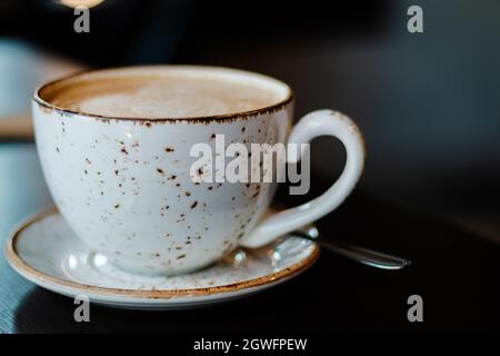 Une tasse de café cappuccino sur la table en bois sombre du café Banque D'Images