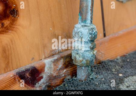 Ancien tuyau présentant une fuite d'eau et des dépôts de calcaire sur l'ancien tapis et les panneaux en bois Banque D'Images