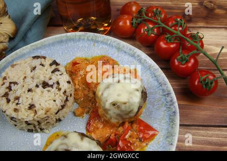 Gros plan de la plaque bleue sur une table en bois avec des boulettes de viande hachées maison grainées au fromage mozzarella dans une sauce tomate fraîche avec du riz Banque D'Images