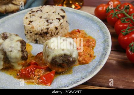 Gros plan de la plaque bleue sur une table en bois avec des boulettes de viande hachées maison grainées au fromage mozzarella dans une sauce tomate fraîche avec du riz Banque D'Images