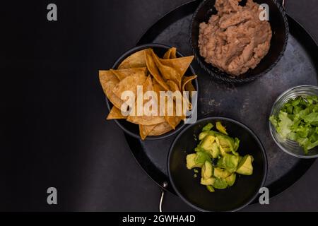 Bols de croustilles tortilla, haricots réfrits et avocat haché sur la comal mexicaine Banque D'Images