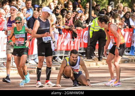 Londres, Royaume-Uni. 03ème octobre 2021. Un coureur qui s'effondre est aidé sur le dernier mile à Birdcage Walk. Après une absence de 2 ans, le Virgin Money London Marathon est de retour à son parcours traditionnel de Blackheath au Mall. Il est prévu d'être le plus grand marathon organisé n'importe où, avec plus de 40,000 participants, et un nombre similaire de terminer le marathon virtuel sur un parcours de leur choix simultanément. Credit: Imagetraceur/Alamy Live News Banque D'Images