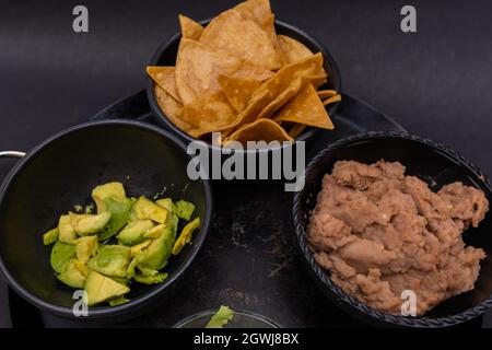 Bols de croustilles tortilla, avocats hachés et haricots réfrits sur la comal mexicaine Banque D'Images