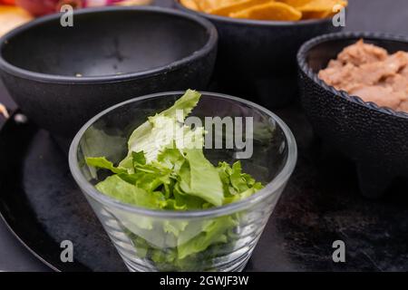 Bols de laitue hachée, croustilles tortilla et haricots réfrits sur la comal mexicaine Banque D'Images